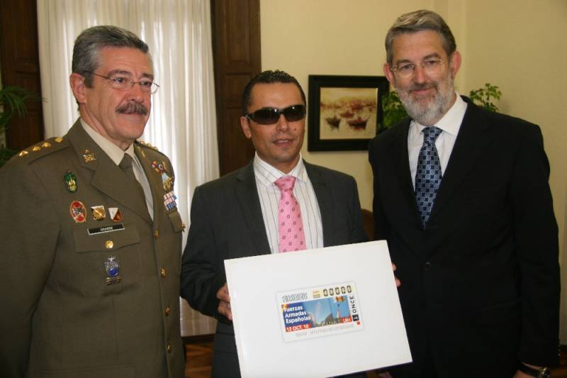El delegado del Gobierno el coronel jefe de la delegación de Defensa y el delegado de la ONCE en Cantabria muestran el cupón.