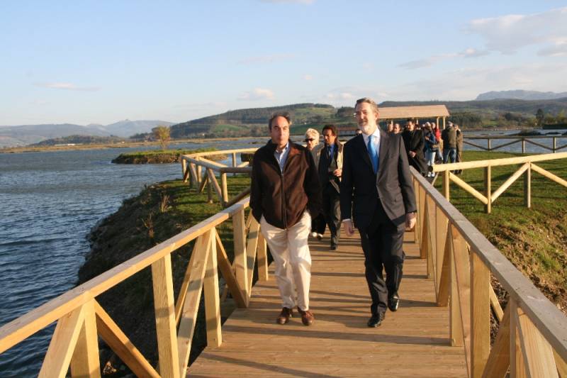 En primer término, el delegado del Gobierno y uno de los concejales de Escalante caminan por la pasarela que conduce al observatorio sobre la Ría