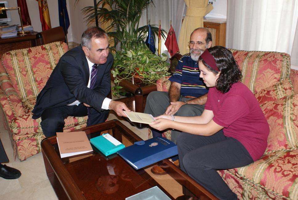 El Delegado del Gobierno, Rafael González Tovar, hace entrega a Ana García de una Constitución Española.