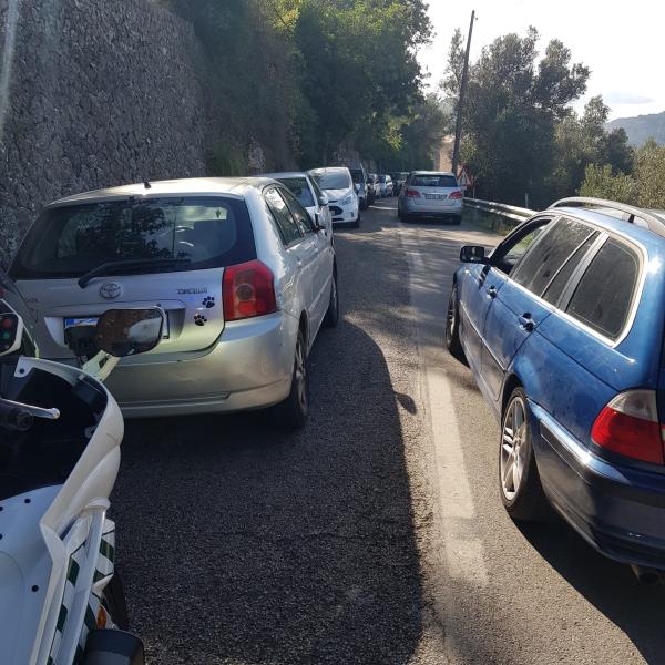 Coches estacionados en la calzada, ocupando un carril de circulación, en una carretera de la Serra de Tramuntana.